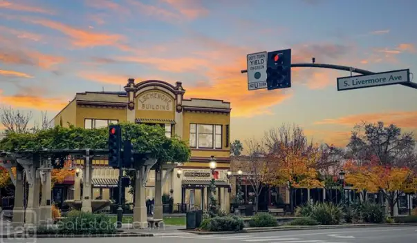 Sunset over a small downtown street with a two-story brick building, traffic lights, and fall-colored trees on S. Livermore Ave.